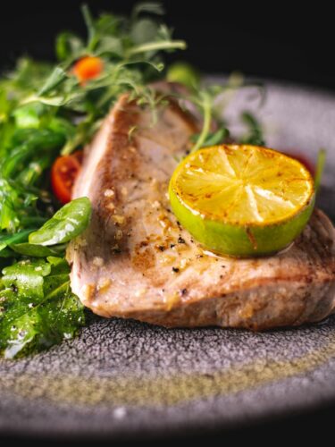 Thunfischsteak Sous Vide wird mit Limette an Salat serviert.