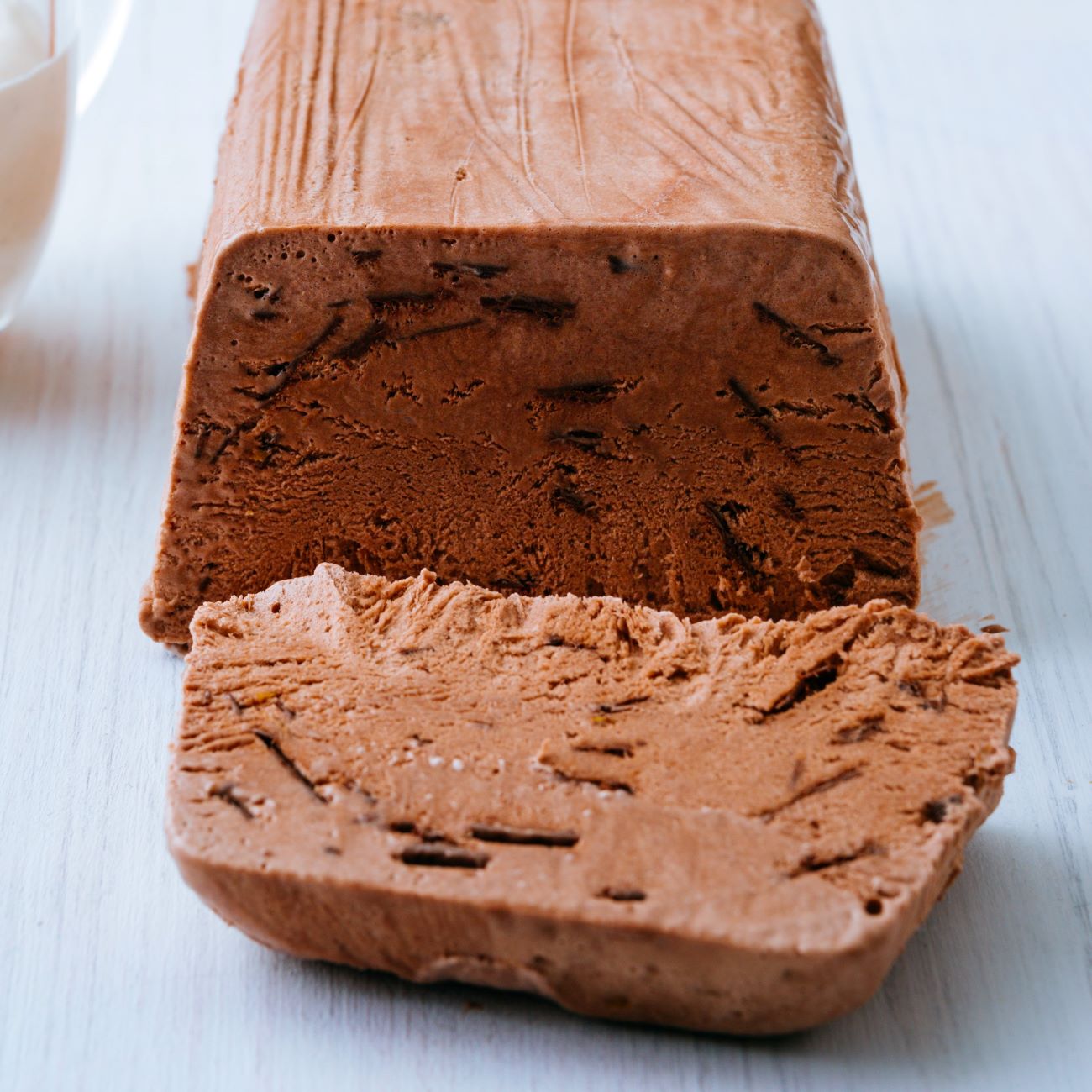 Čokoladni parfait je prikazan razrezan na belem lesenem krožniku.