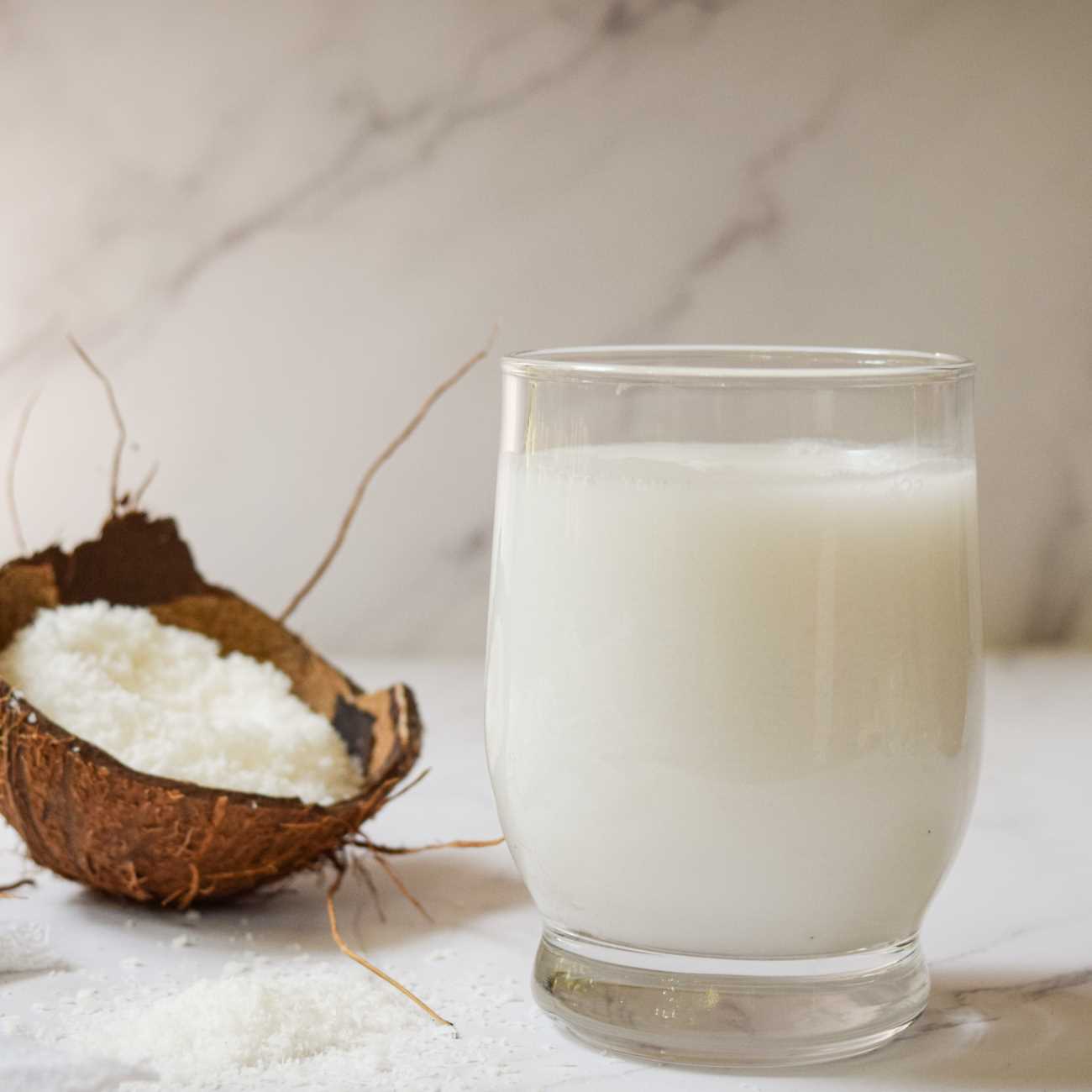 Kokosovo mleko je prikazano s kokosovimi kosmiči in kokosovo lupino.