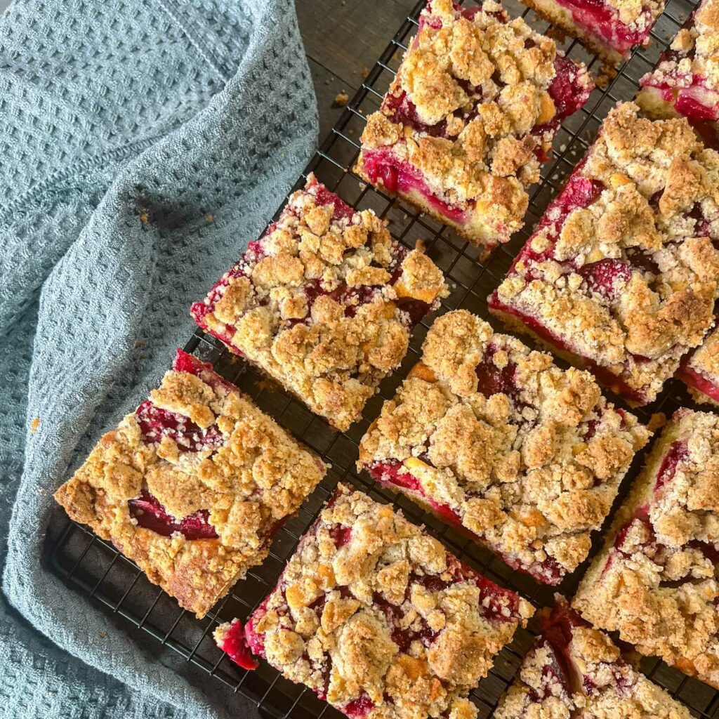 Pflaumenkuchen mit Streusel wird auf einem Kuchengitter gezeigt.