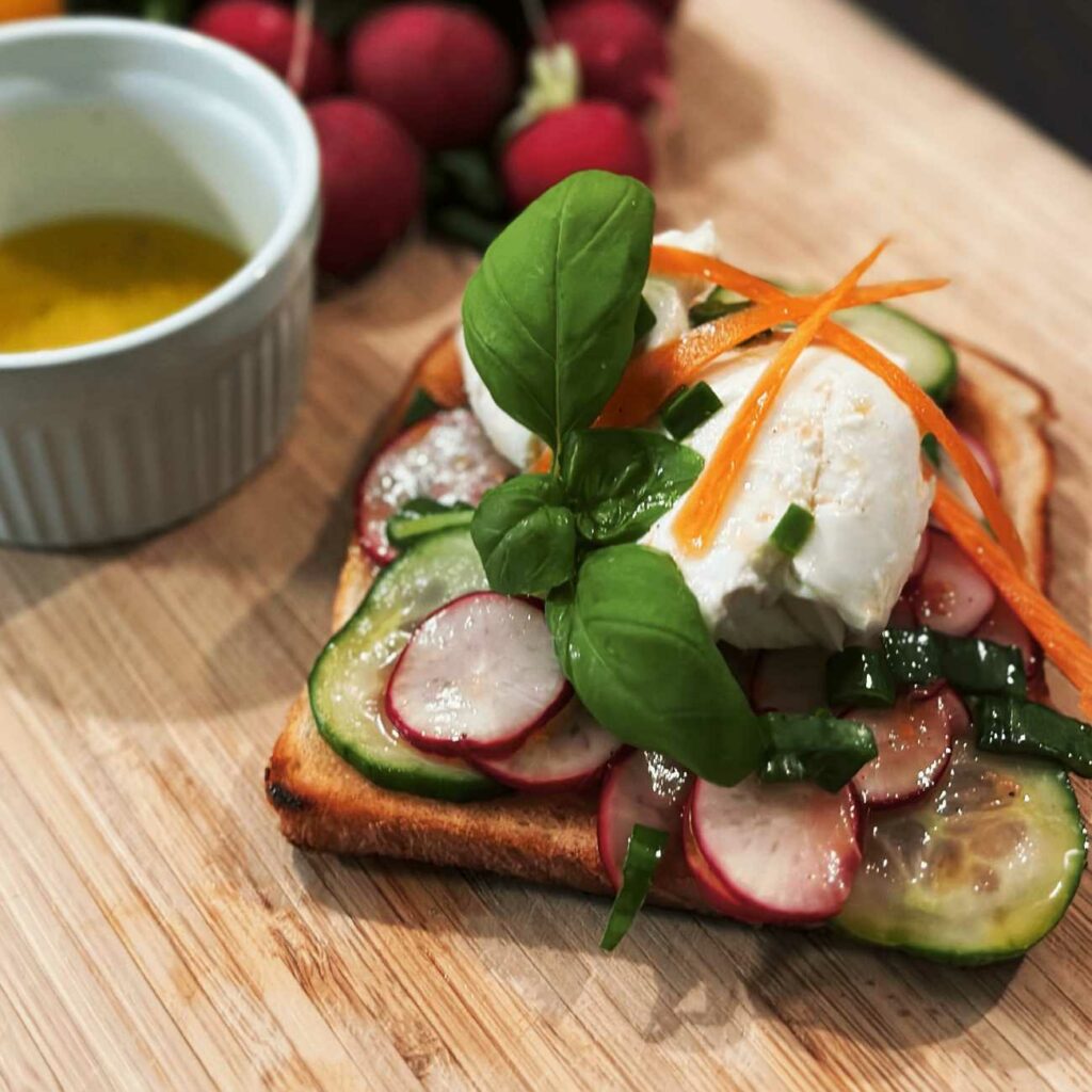 Radieschen Toast wird auf einem Holzbrett mit Radieschen und Vinaigrette gezeigt.