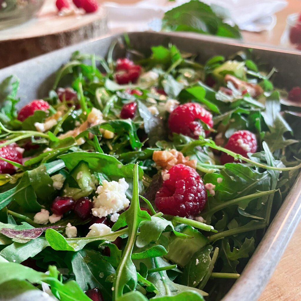 Sommersalat mit Himbeeren wird in einer grauen Schüssel gezeigt.