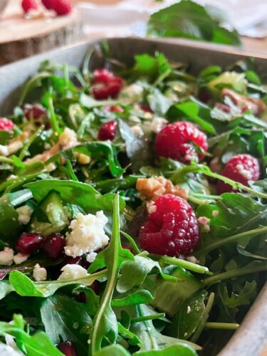 Sommersalat mit Himbeeren wird in einer grauen Schüssel gezeigt.