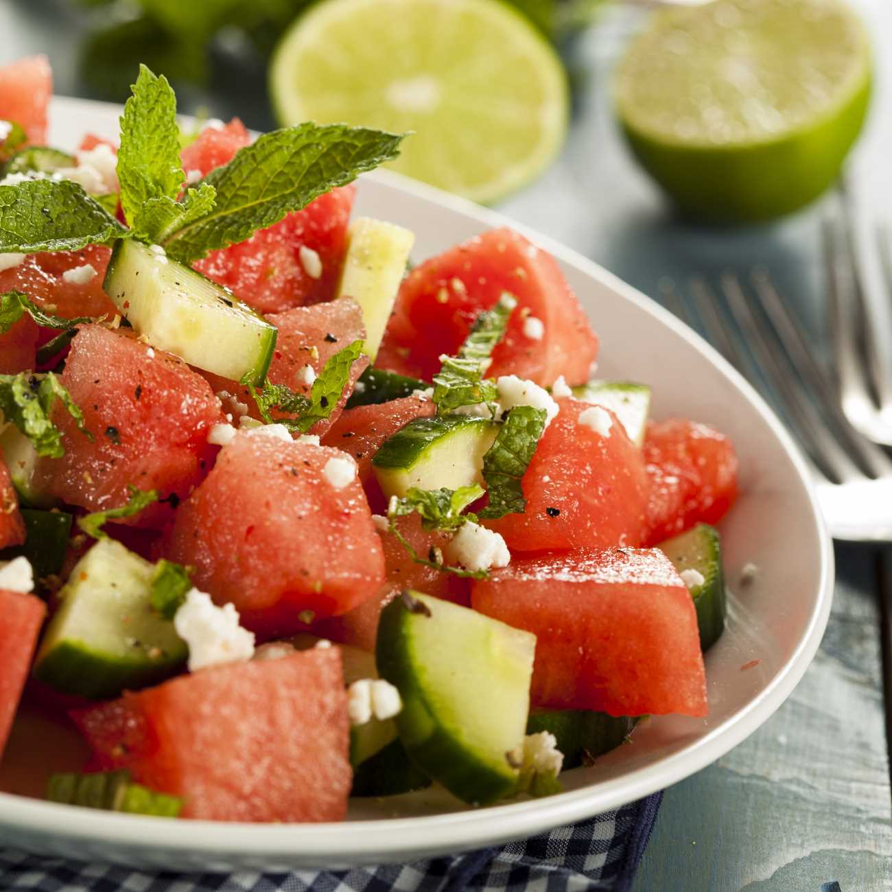 Melonen-Feta-Salat wird auf einem Teller mit Minze garniert präsentiert.