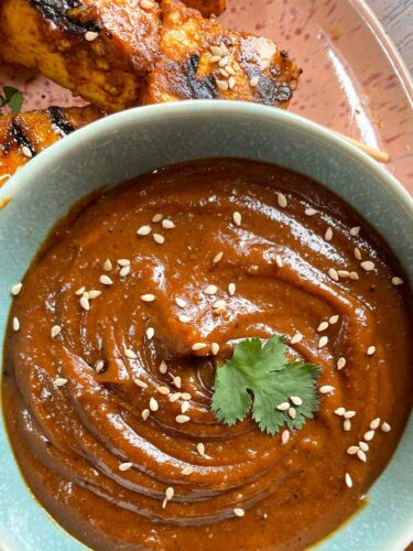 Erdnusssauce wird in einer kleinen, blauen Schüssel mit Tofu Sticks gezeigt.