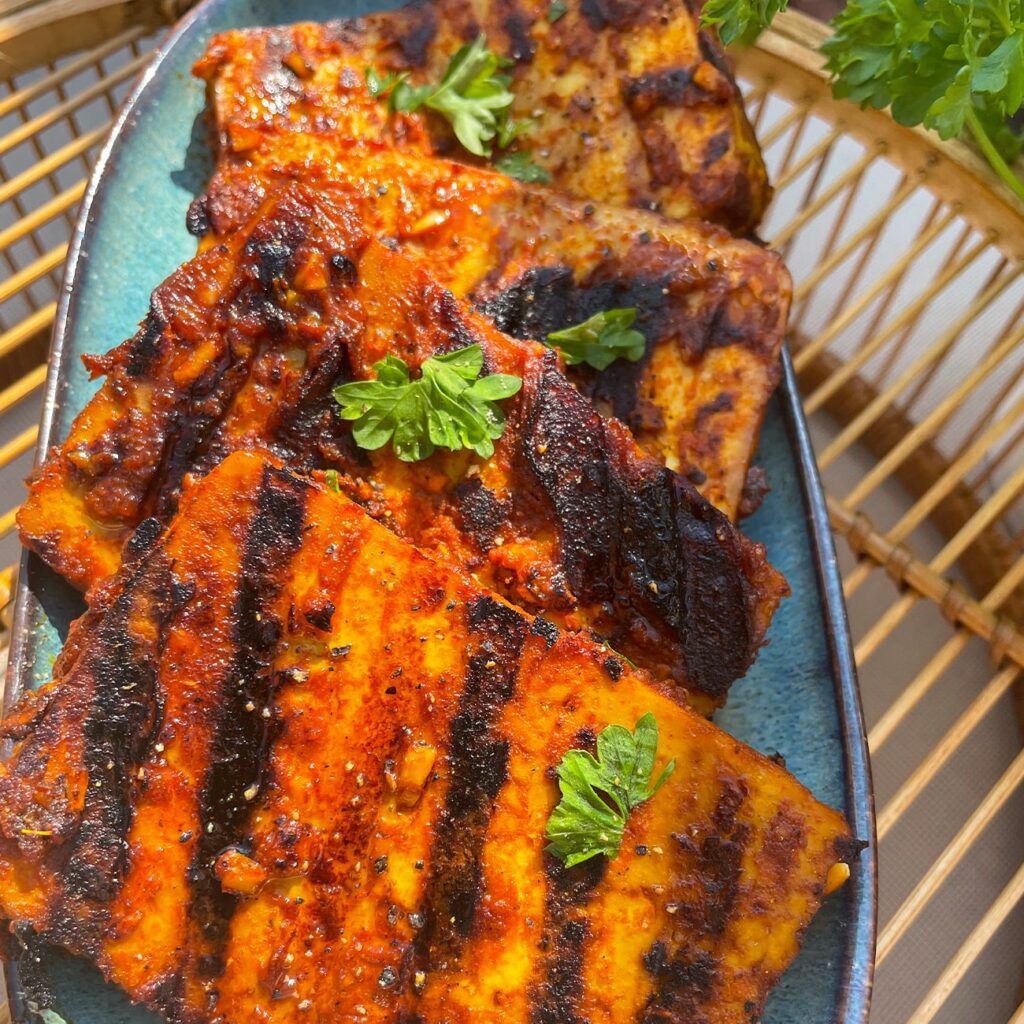 Tofu Steaks werden auf einem länglichen Teller mit Petersilie gezeigt.